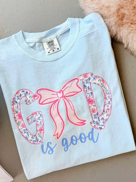 Light blue shirt with floral heart and bow floral God is good design on a neutral background