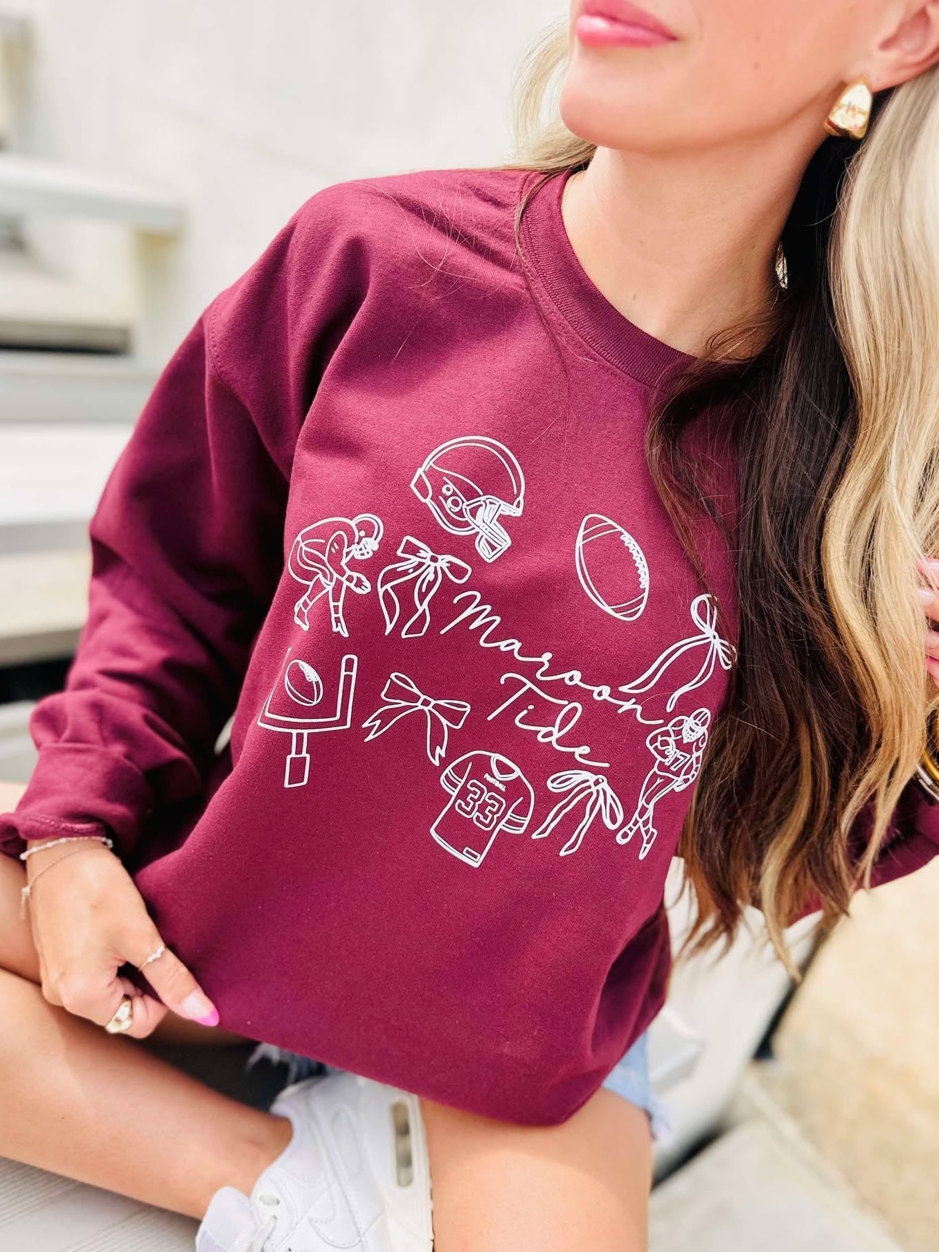 Person wearing a maroon sweatshirt with white graphics and text.
