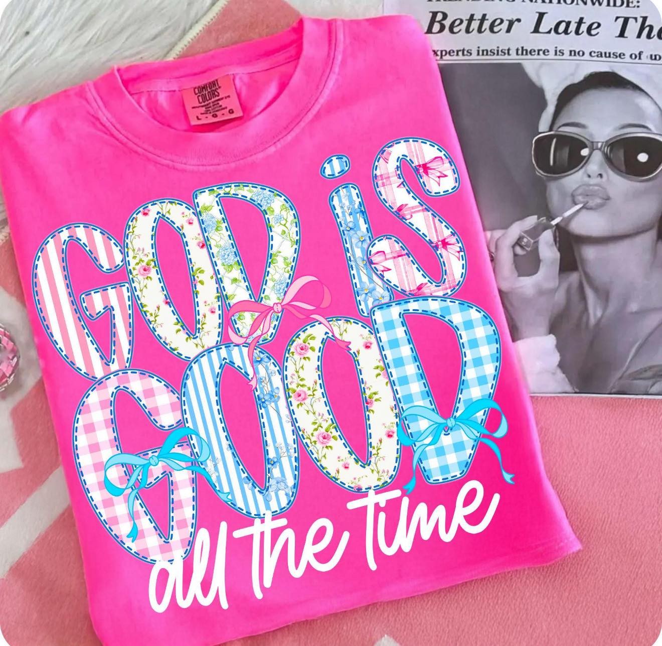 Pink t-shirt with 'God is good all the time' text on a pink surface.