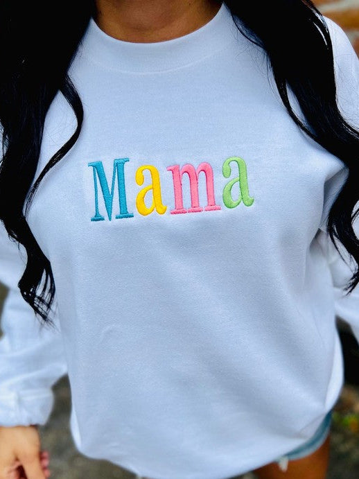 A white sweatshirt with the word 'mama' embroidered in multicolored letters on the front.