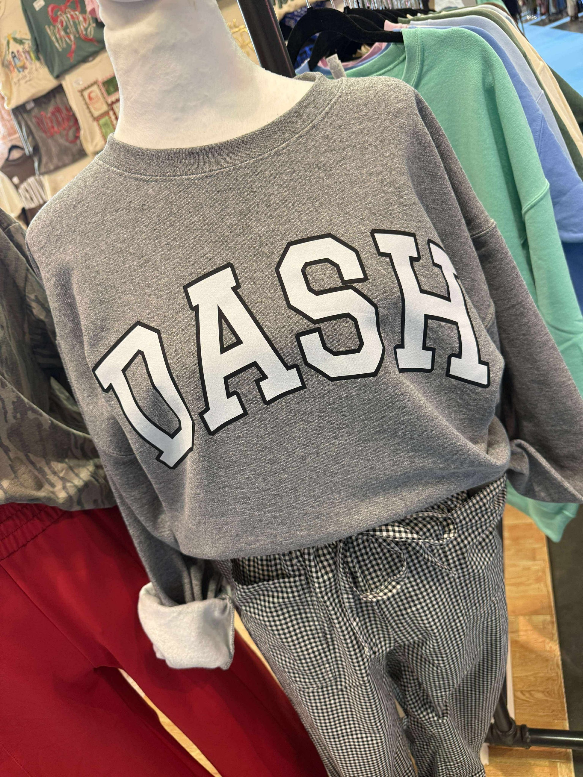 Gray sweatshirt with 'DASH' text on a mannequin in a store setting