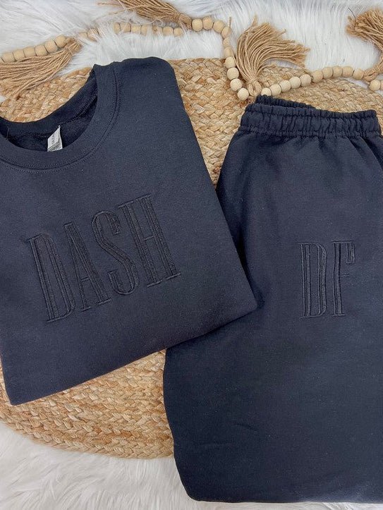 Navy blue sweatshirt and pants with 'DASH' and 'DF' text on a woven mat.
