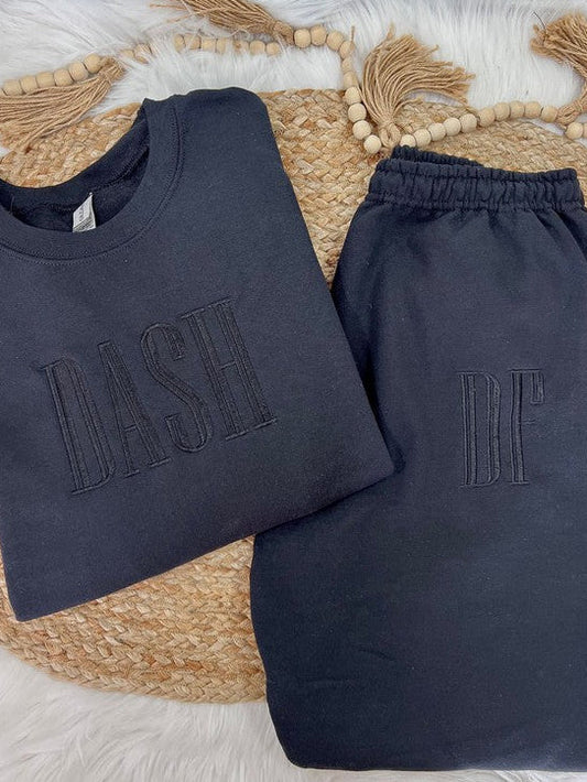 Navy blue sweatshirt and pants with 'DASH' and 'DF' text on a woven mat.