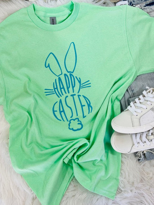 Light green t-shirt with 'Happy Easter' design on a fluffy white surface with sneakers.
