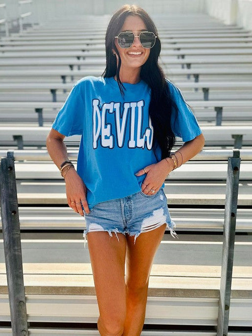 Person wearing a blue 'DEVIL' t-shirt in bleacher seating area