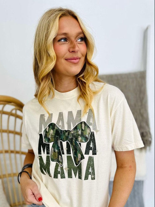 Woman wearing a white t-shirt with 'MAMA' text and camouflage bow design.