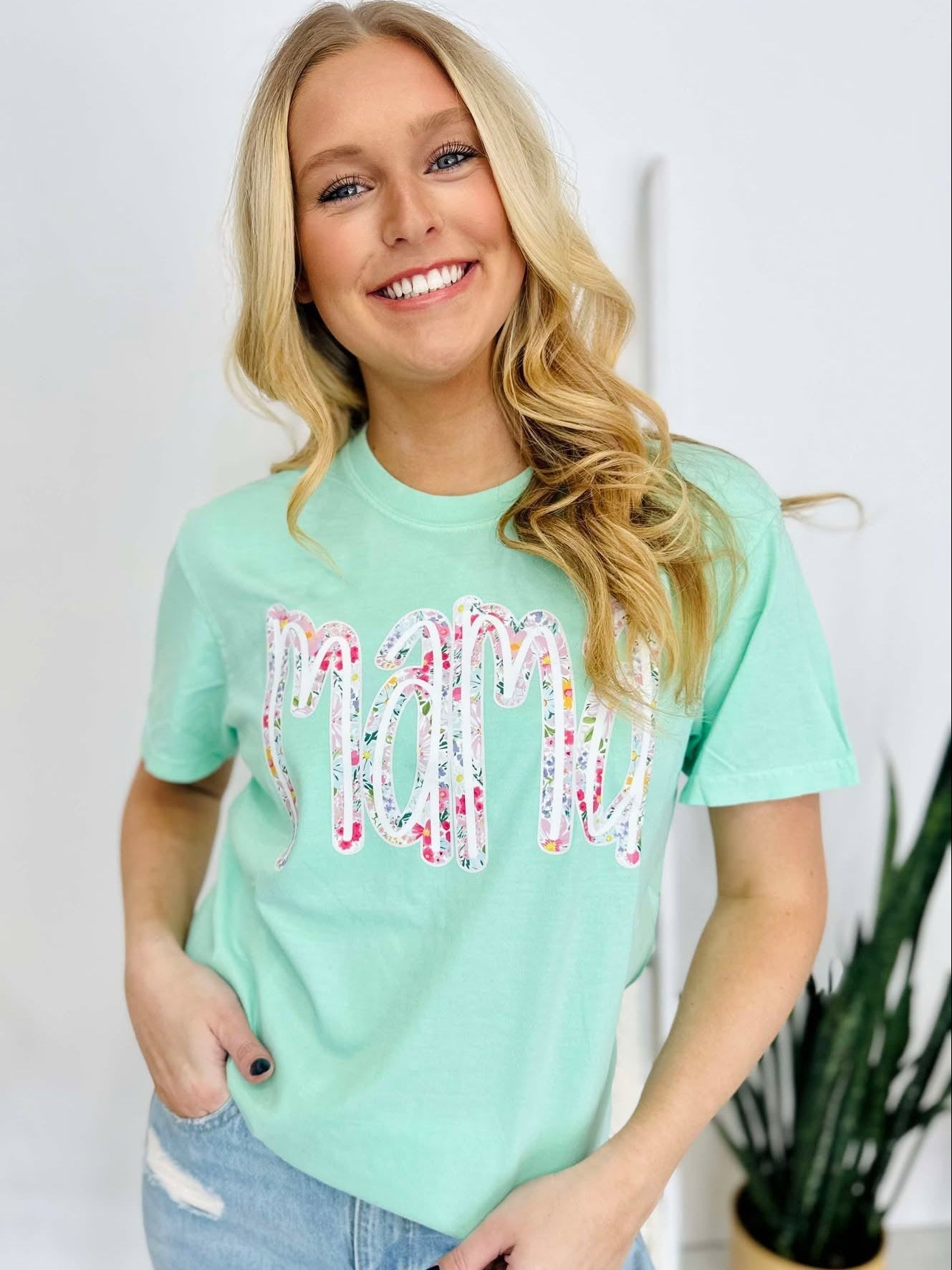 A woman smiling and wearing a green t-shirt with a multicolored floral farm DTF print.