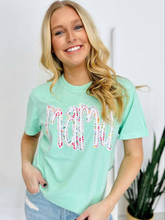 A woman smiling and wearing a green t-shirt with a multicolored floral farm DTF print.