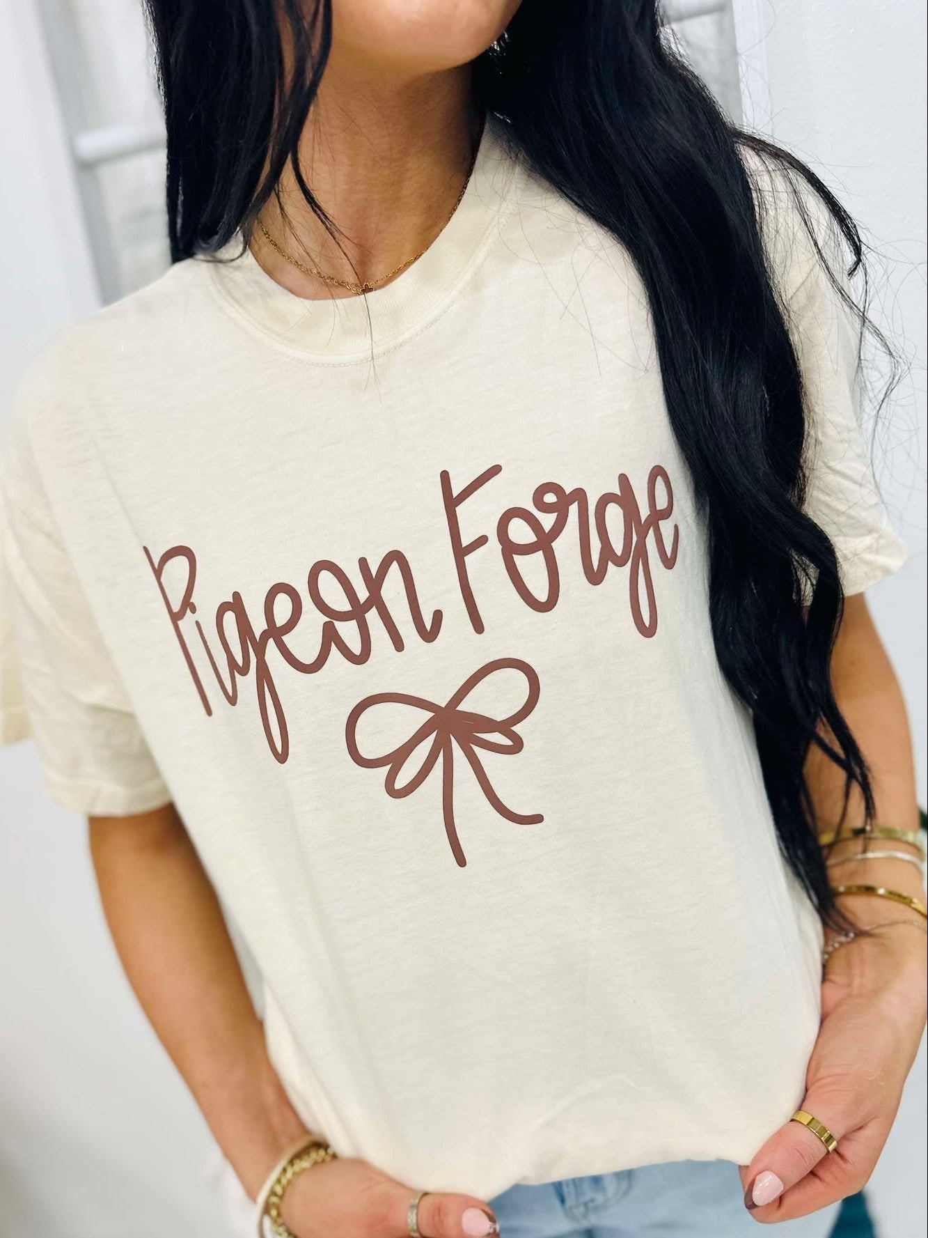 Person wearing a white t-shirt with 'Pigeon Forge' text and bow graphic.