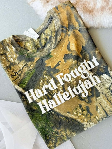A Real Tree camouflage graphic tee with the text 'Hard Fought Hallelujah' printed in white vinyl on the front.