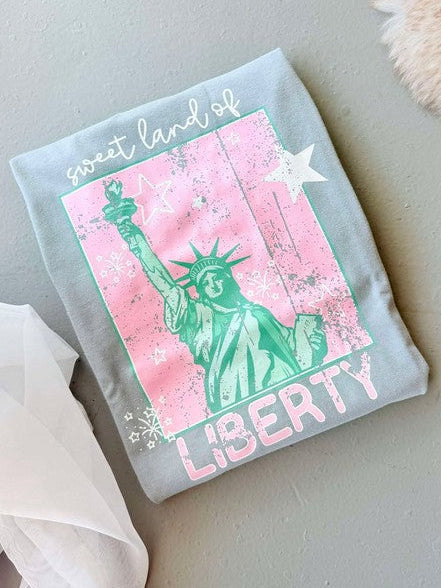 A gray t-shirt with a graphic of the Statue of Liberty in pink and green against a pink background, with the text 'LIBERTY' below the statue.
