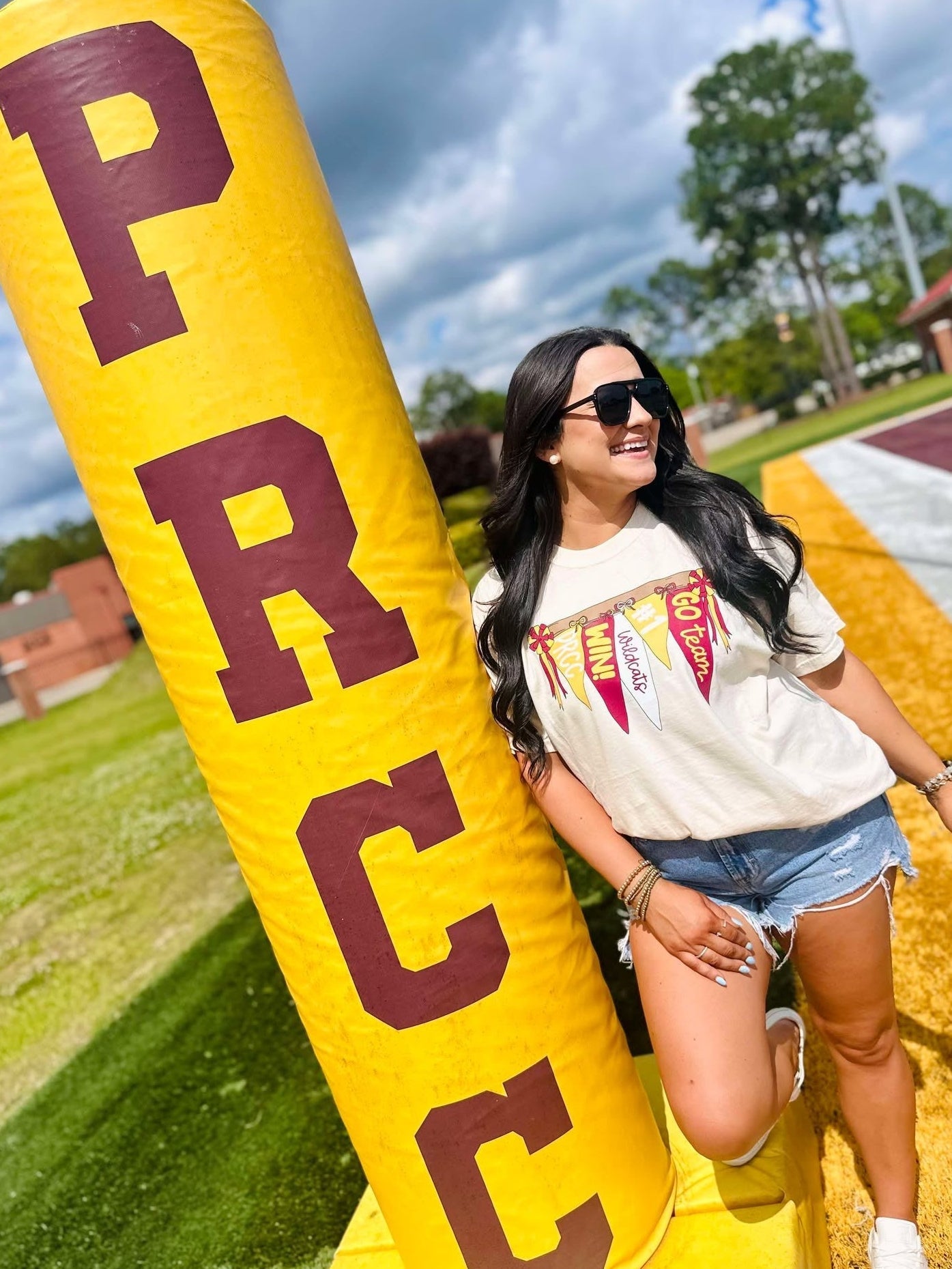 Woman posing with a large yellow and red 'PRC' inflatable tube on a grassy field.