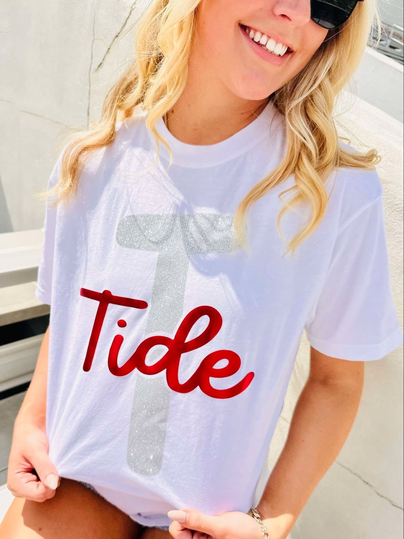 Person wearing a white t-shirt with 'Tide' printed on it, sitting outdoors.