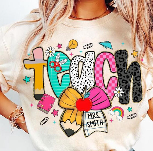 T-shirt with colorful 'TEACH' design and personalized name on a plain background