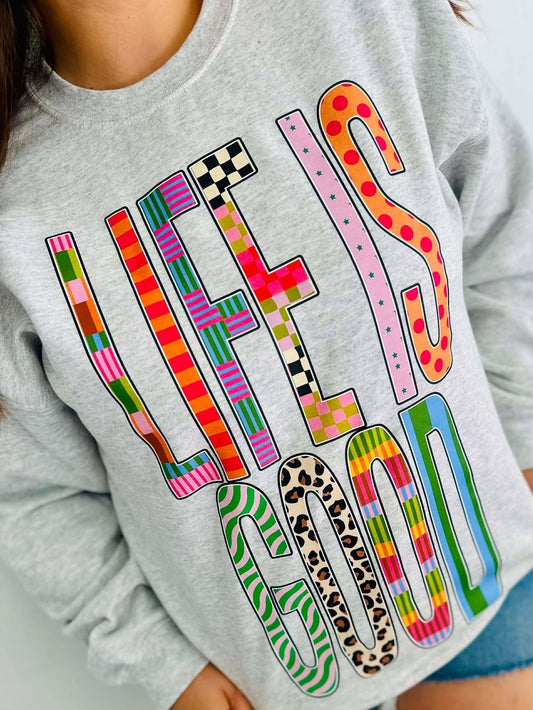 Gray sweatshirt with colorful text design worn by a person.