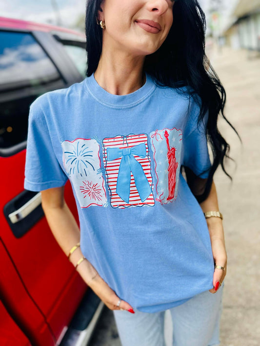 Woman wearing a blue t-shirt with graphic designs, standing next to a red car.