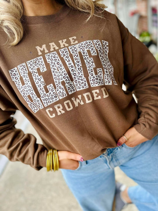 Person wearing a brown sweatshirt with text and leopard print design, standing on a sidewalk.