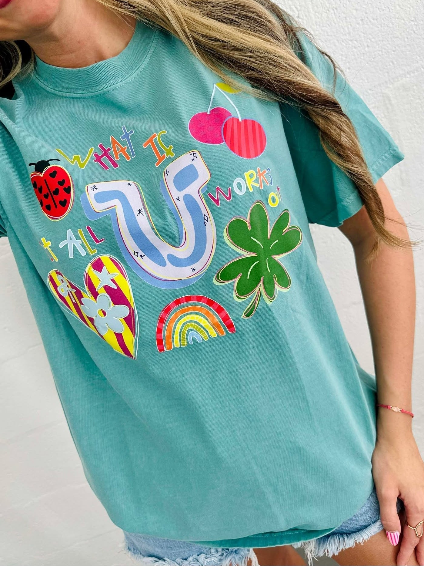 Person wearing a teal t-shirt with colorful graphics and text.
