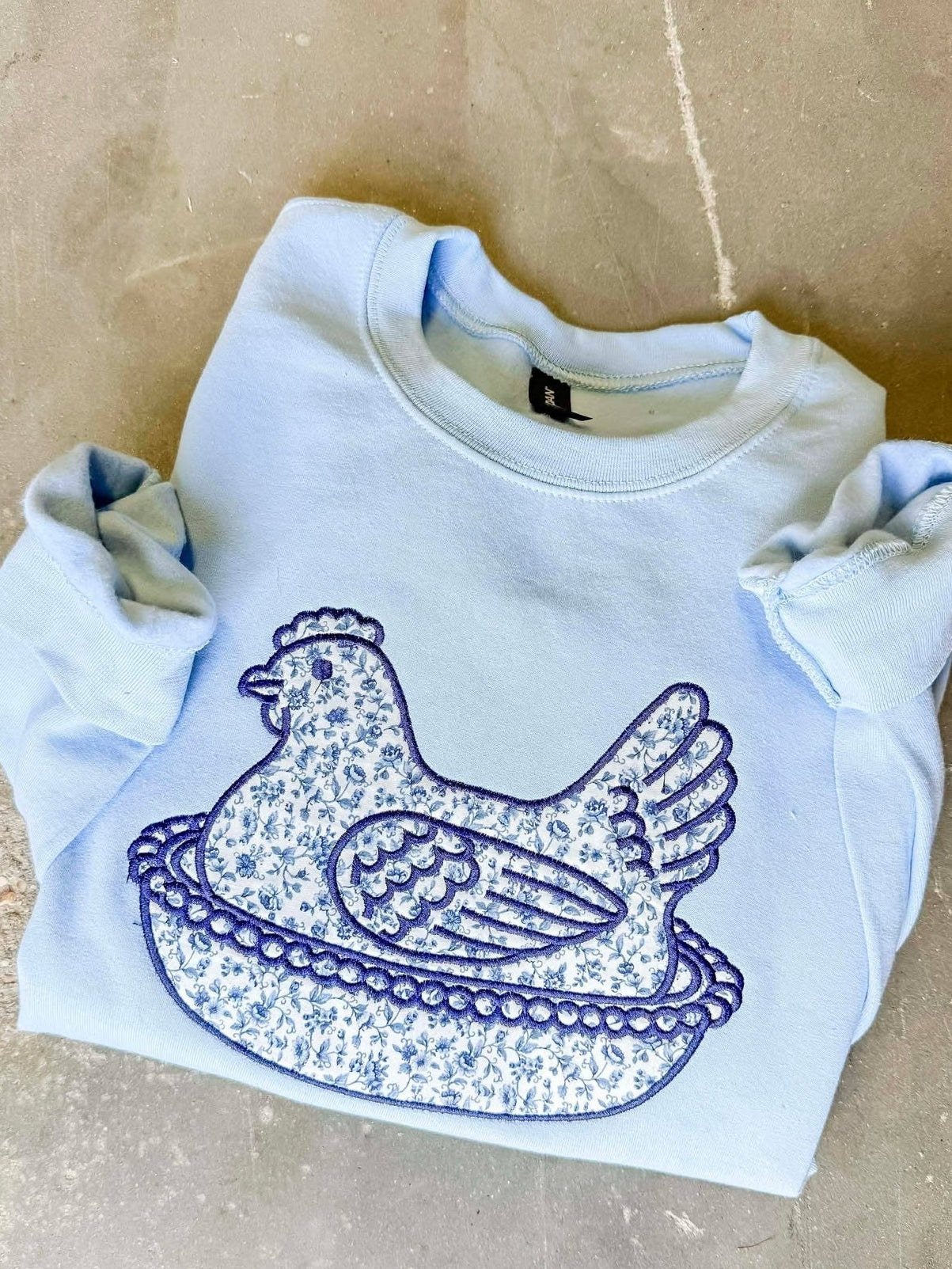 White sweatshirt with blue graphic design on a beige surface