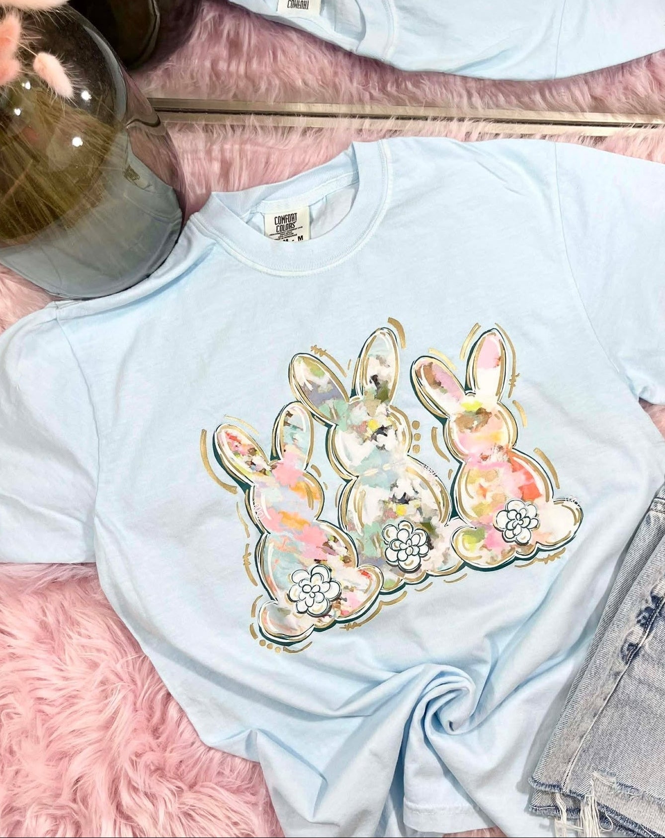 Light blue t-shirt with water color brushed floral bunny design on a pink surface