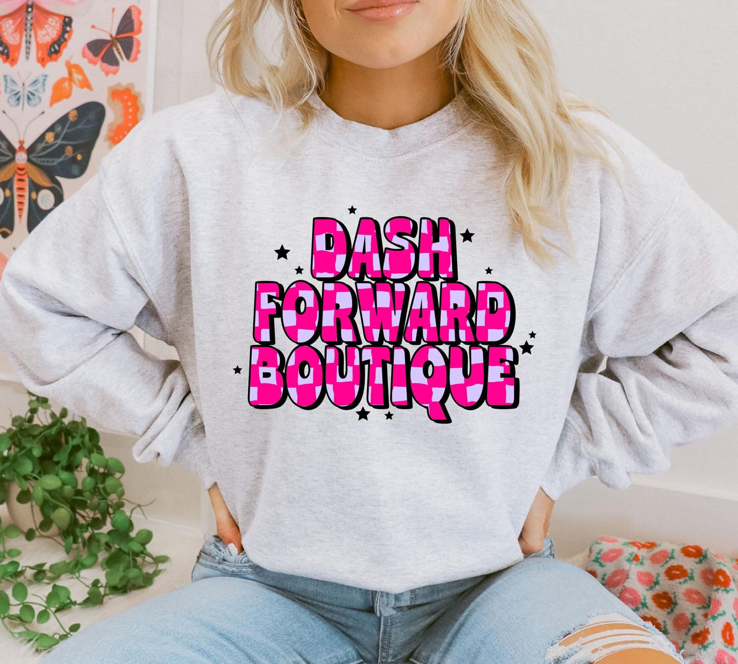 A woman wearing a gray sweatshirt with 'DASH FORWARD BOUTIQUE' text in pink on the front.