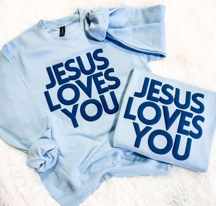 Two light blue sweatshirts with the text 'JESUS LOVES YOU' printed in blue puff vinyl on a white surface.