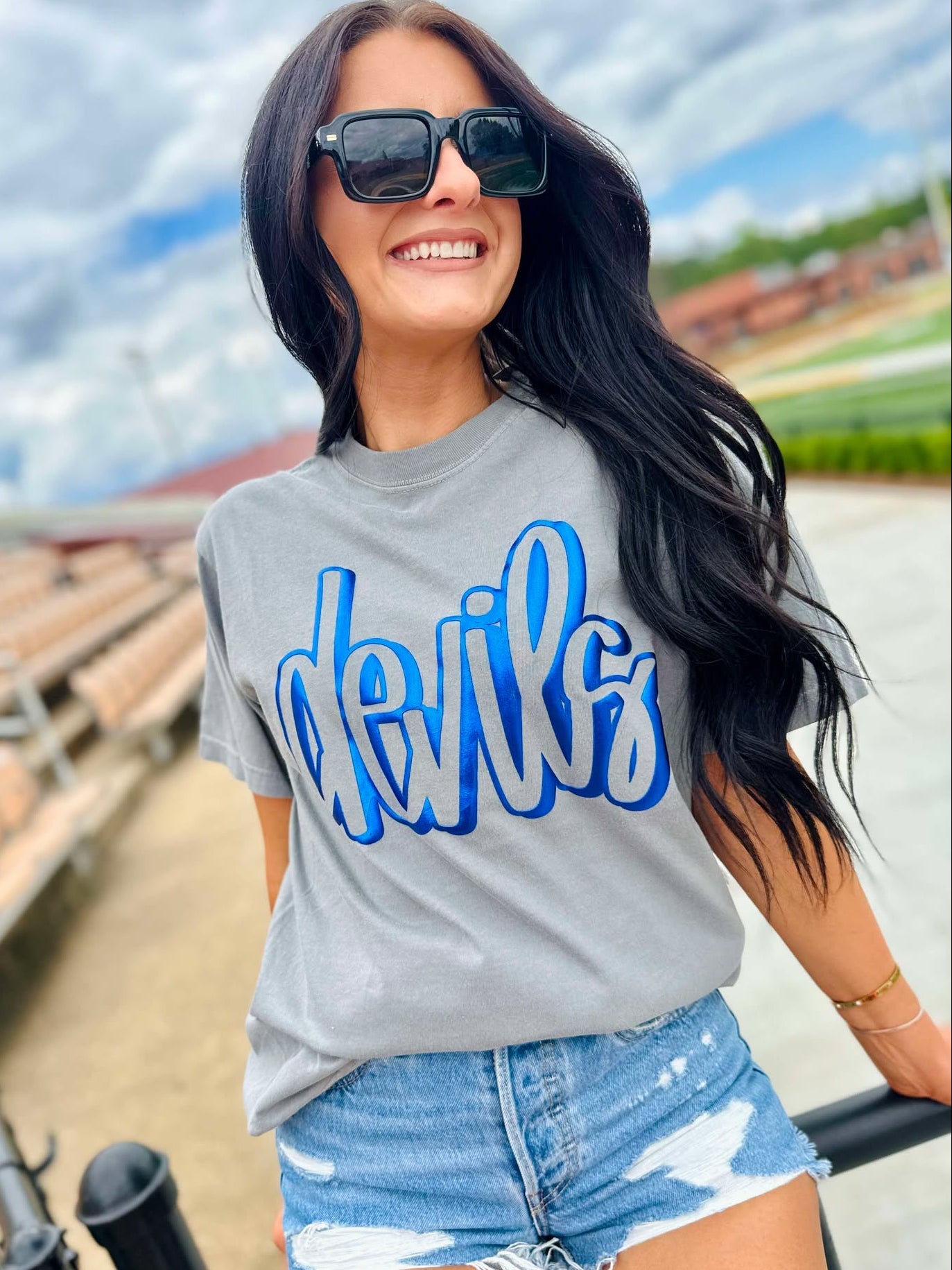 Woman wearing a gray t-shirt with blue text outdoors