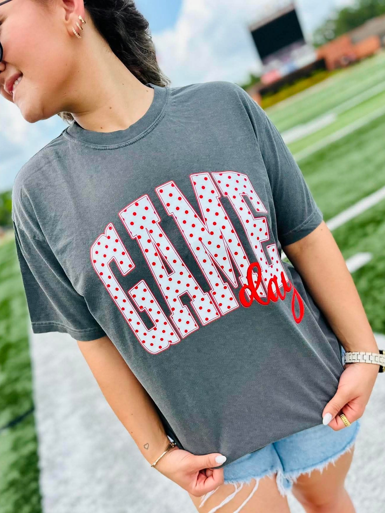 Person wearing a gray t-shirt with 'Gang' printed on it, standing on a grassy field.
