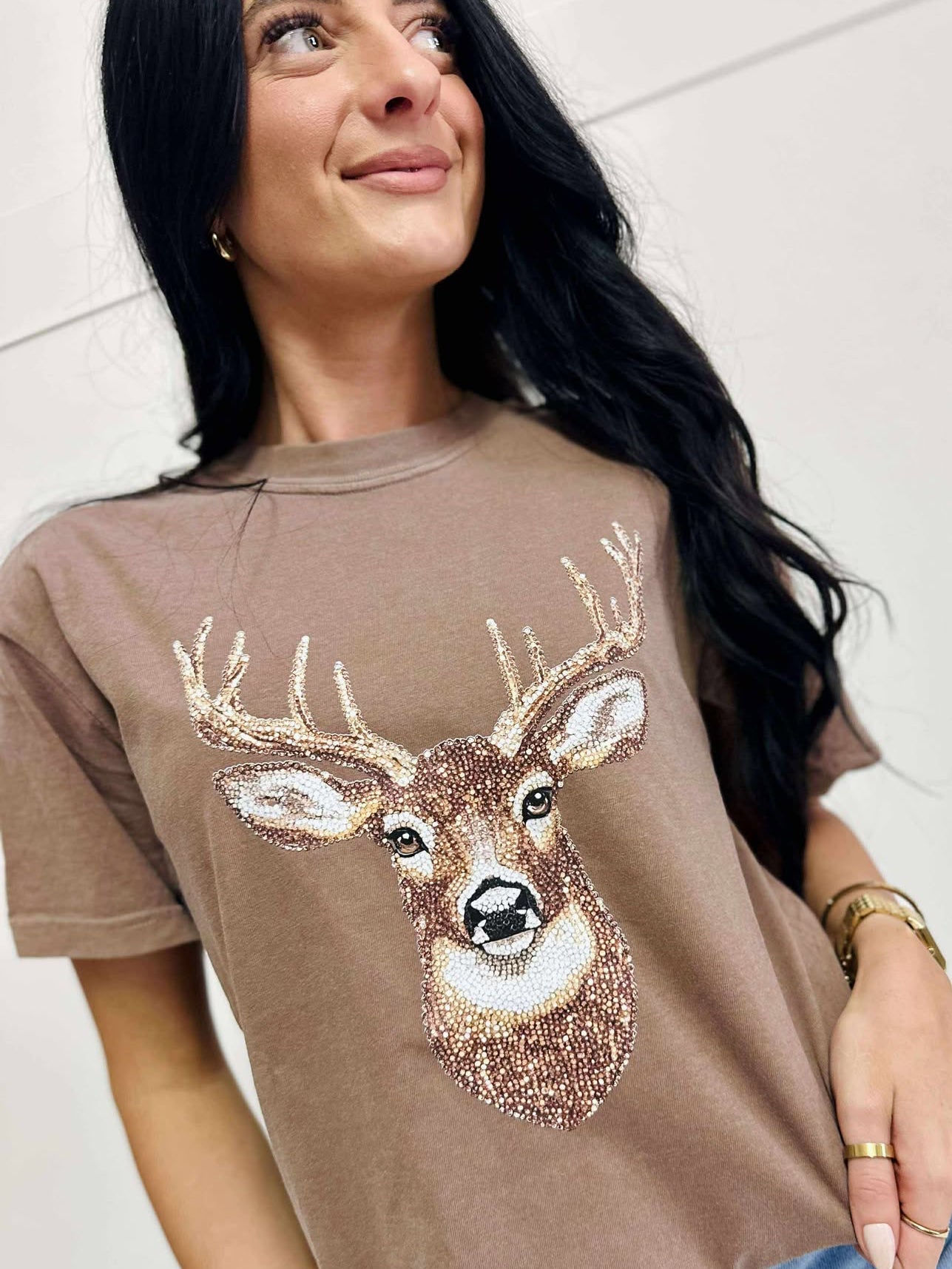 Woman wearing a Espresso t-shirt with a deer graphic design.