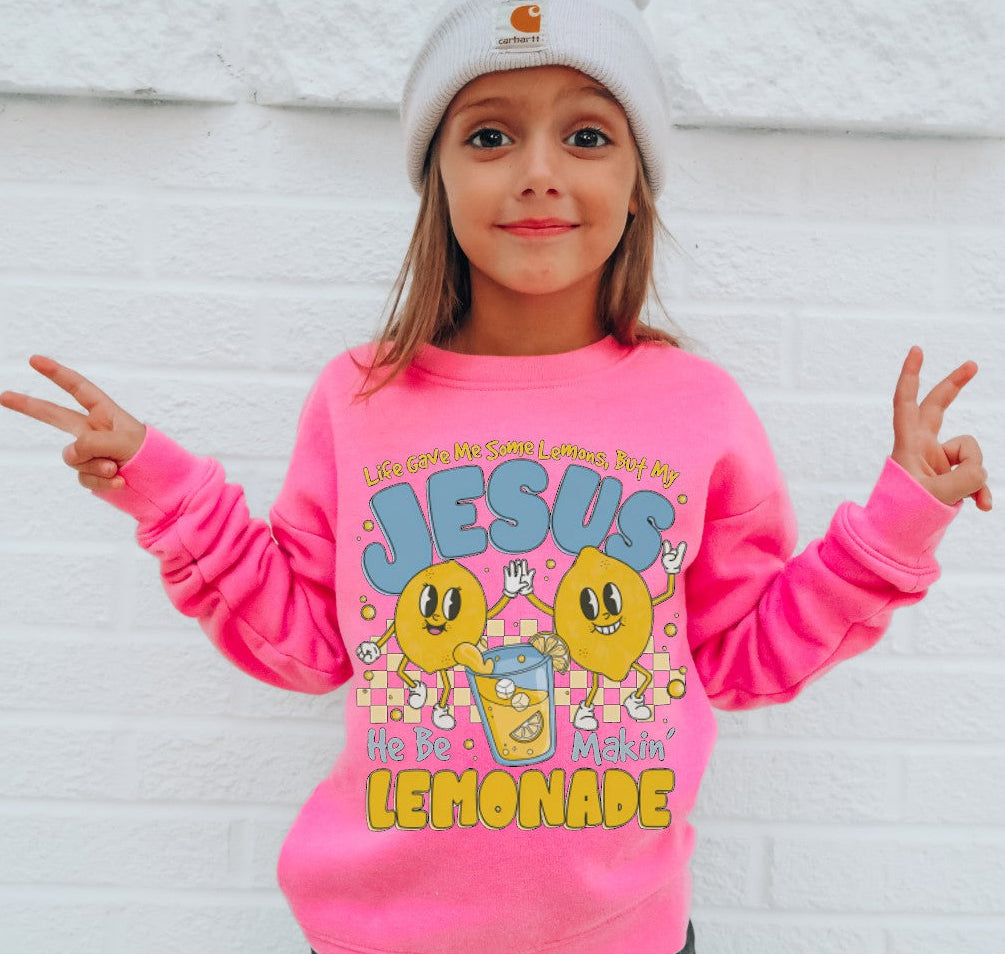 Child wearing a pink sweatshirt with colorful graphics and text, standing against a white background.