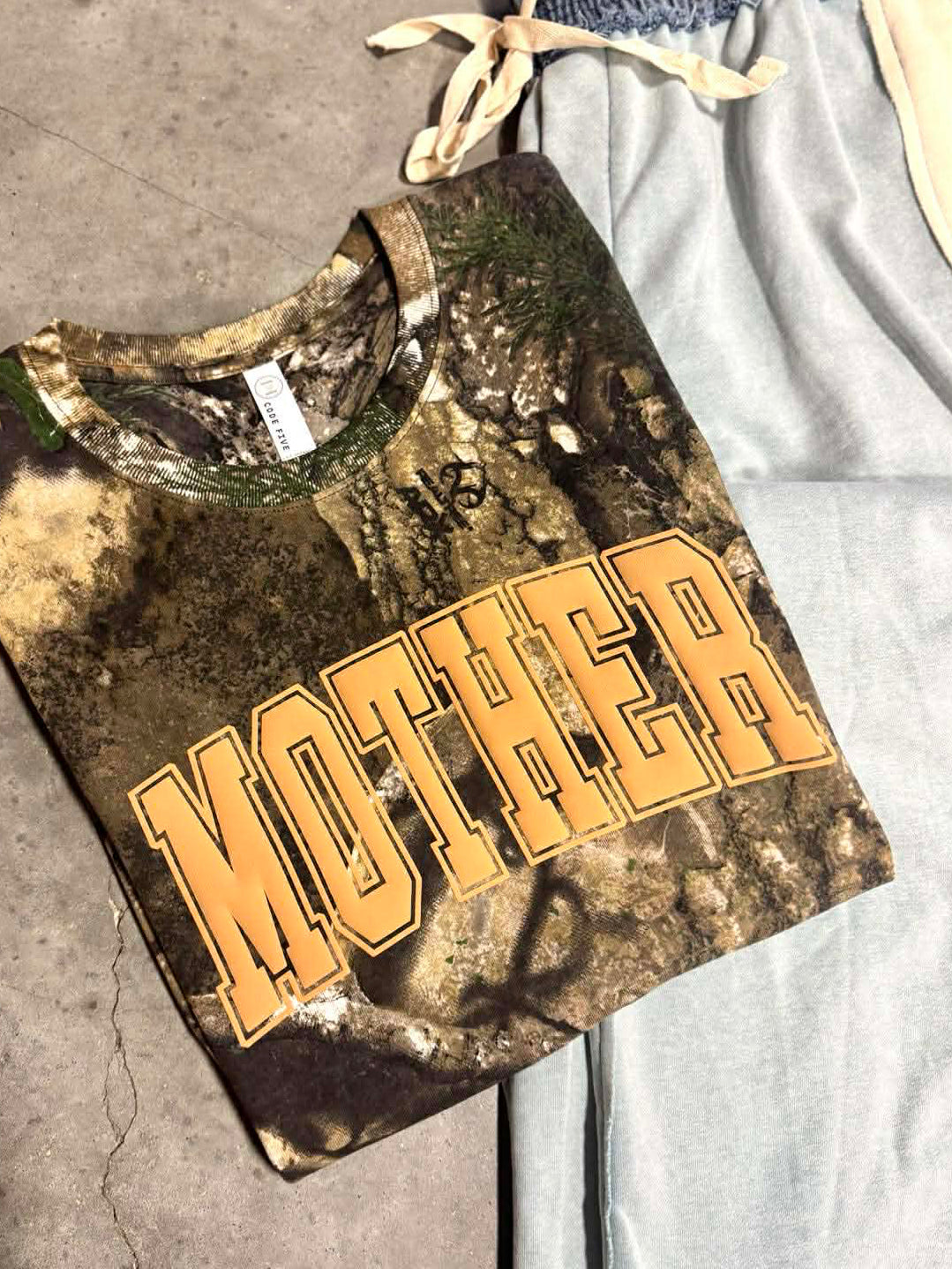 Realtree Camouflage t-shirt with 'MOTHER' text on a concrete surface