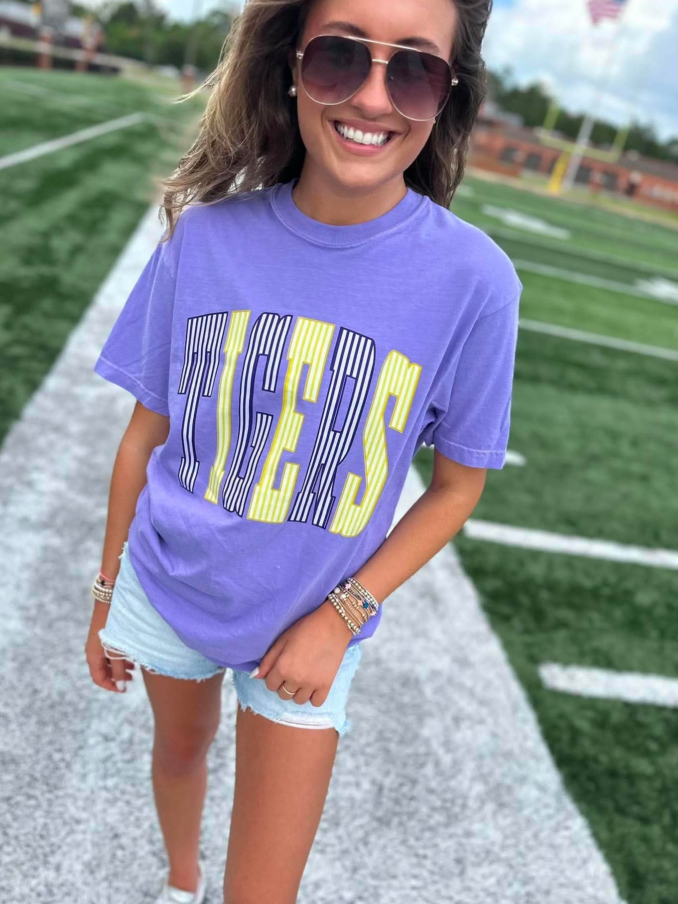 Woman wearing a purple t-shirt with yellow text on a sports field