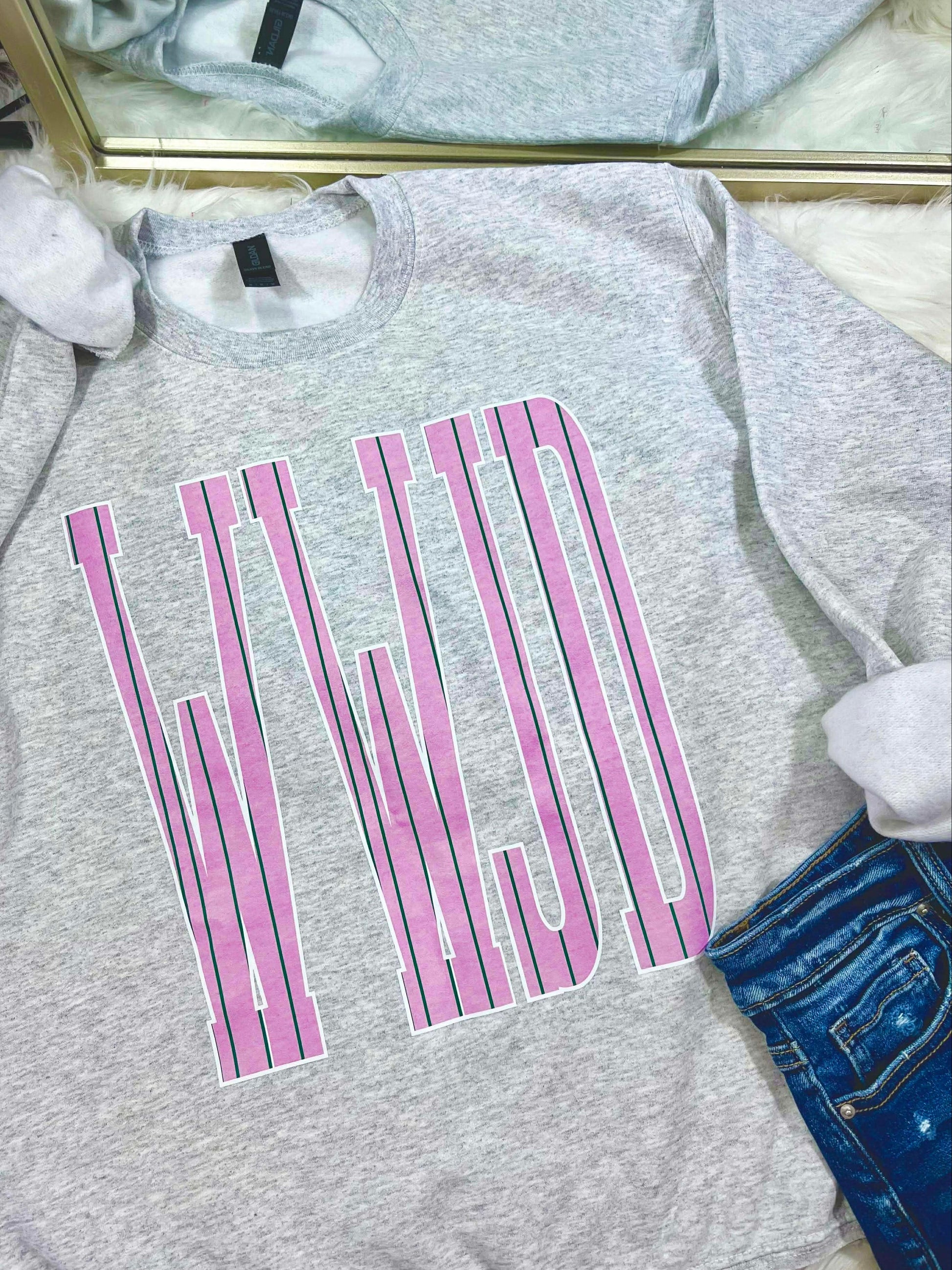 Gray sweatshirt with pink and green stripe WWJD text design on a white surface