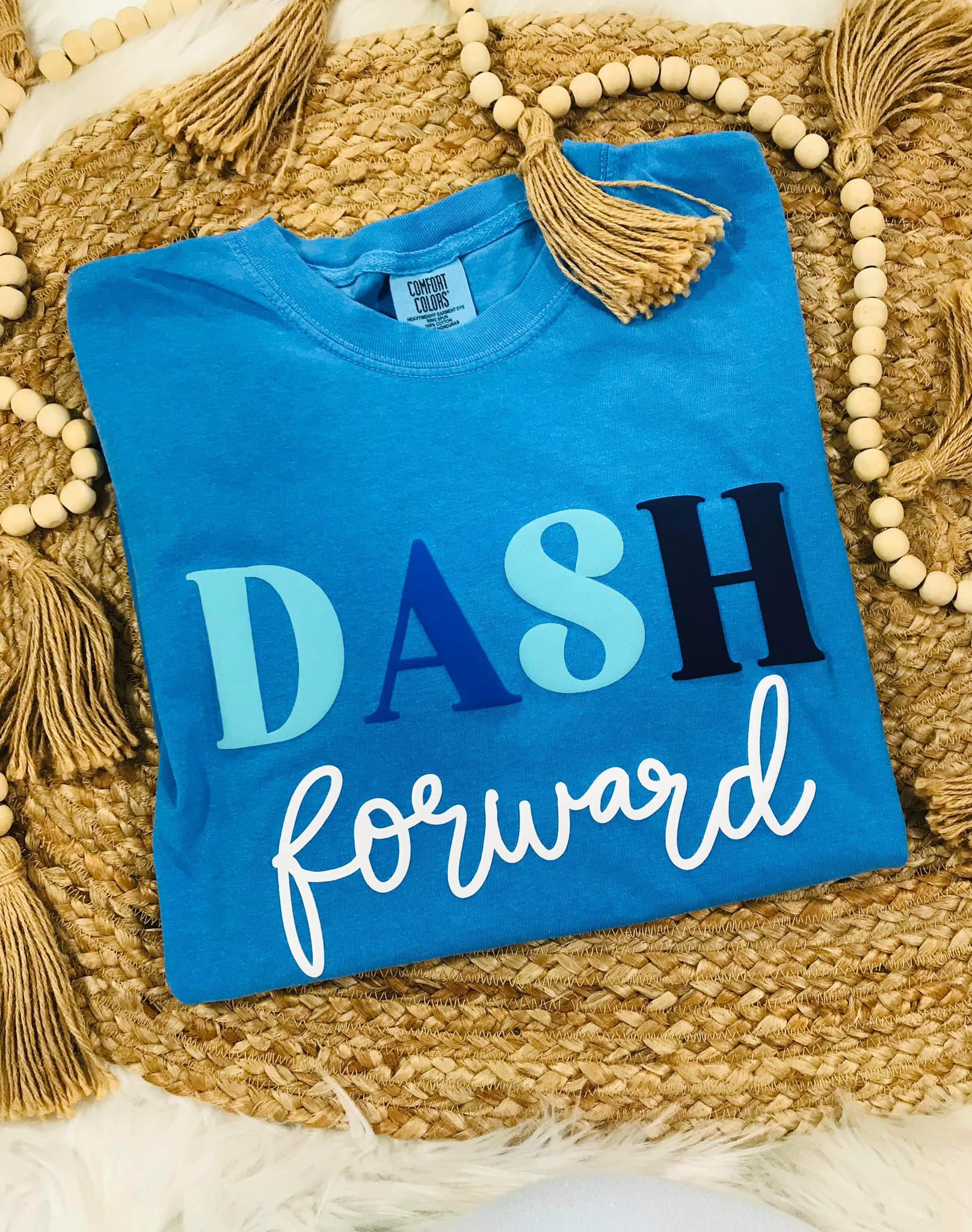 Blue t-shirt with 'DASH forward' text on a woven surface