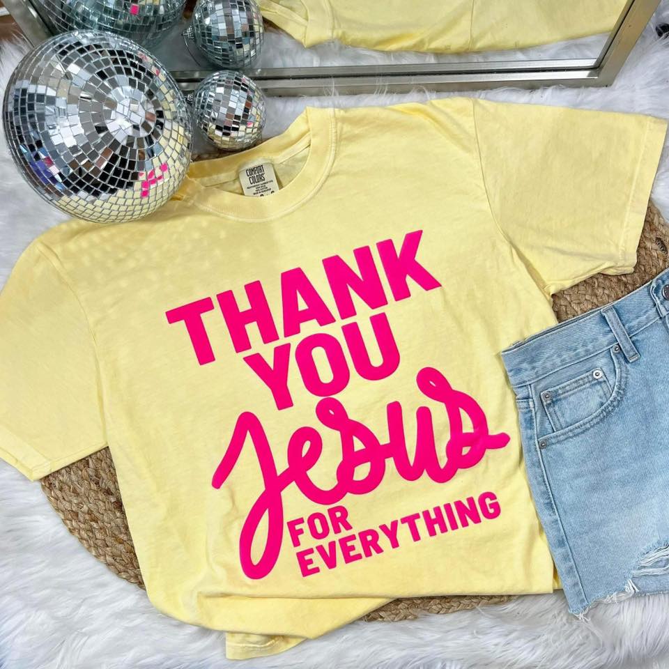 Yellow t-shirt with 'Thank you Jesus for everything' text, disco ball, and jeans on a fluffy surface.