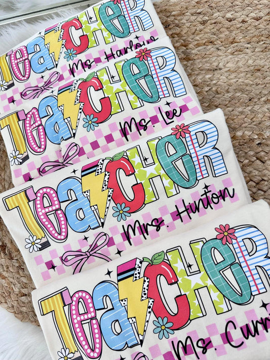 Colorful 'Teacher' nameplates with personalized text on a textured surface.