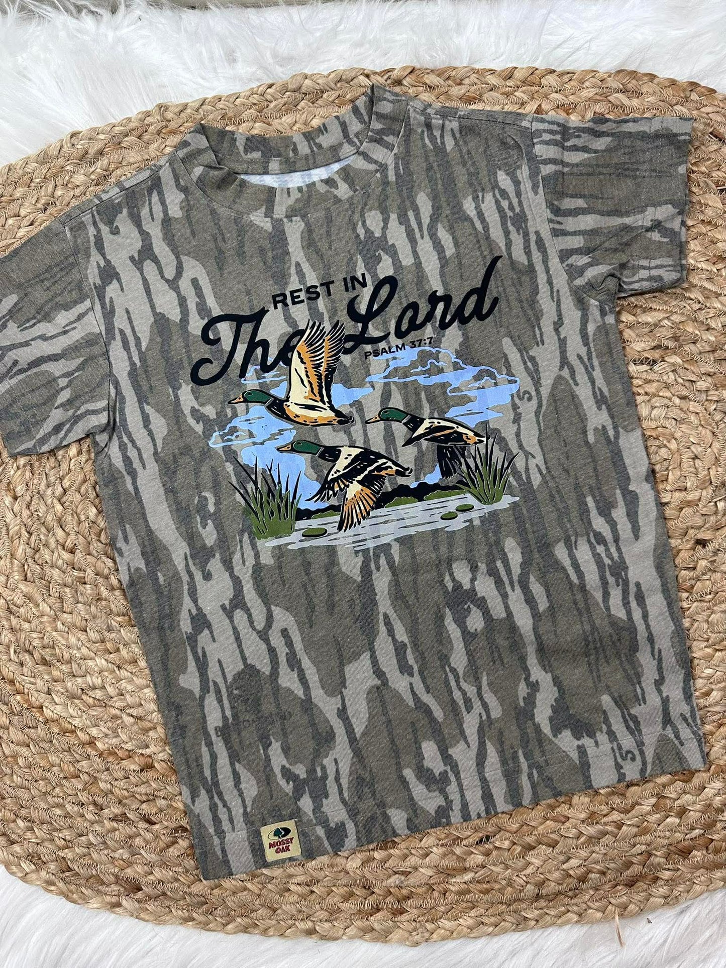 Camouflage-patterned t-shirt with duck design and text on a woven surface