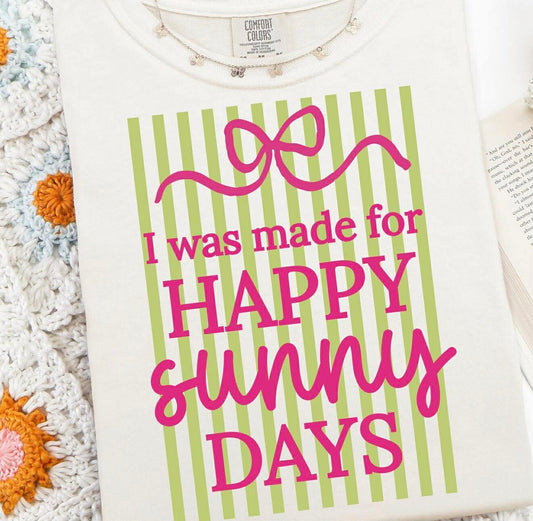White shirt with green stripes and pink text 'I was made for HAPPY SUNNY DAYS' on a textured surface.