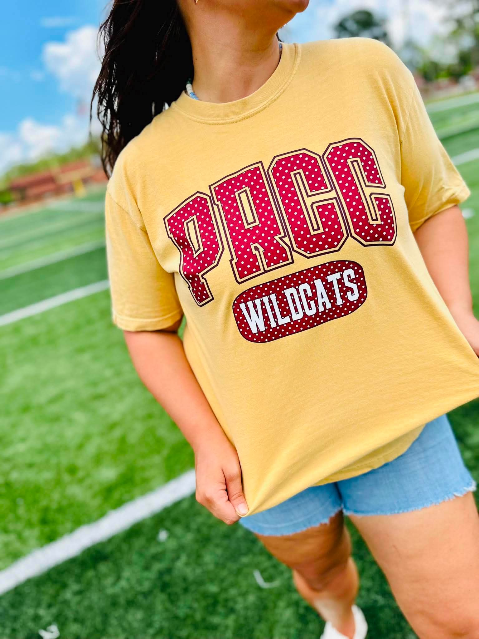 Person wearing a yellow t-shirt with 'PRCC Wildcats' text on a sports field.