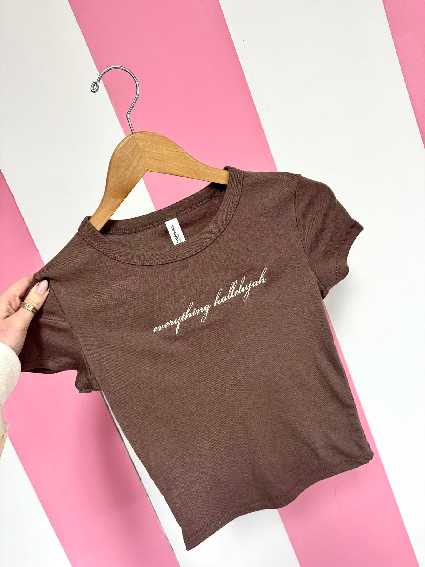 Brown t-shirt with 'everything hallelujah' text on a pink and white striped background