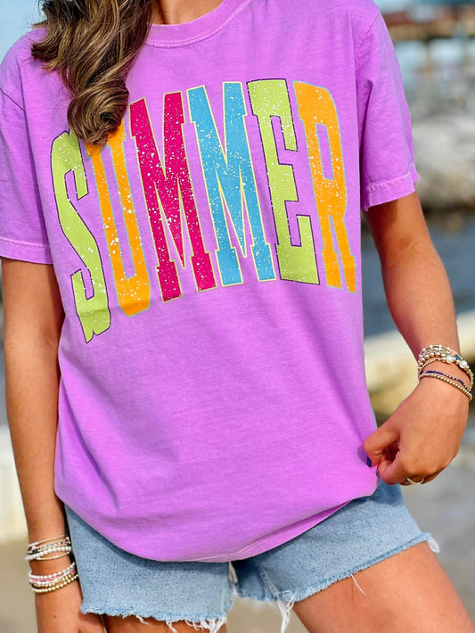 Person wearing a purple t-shirt with 'SUMMER' in colorful letters, standing outdoors.