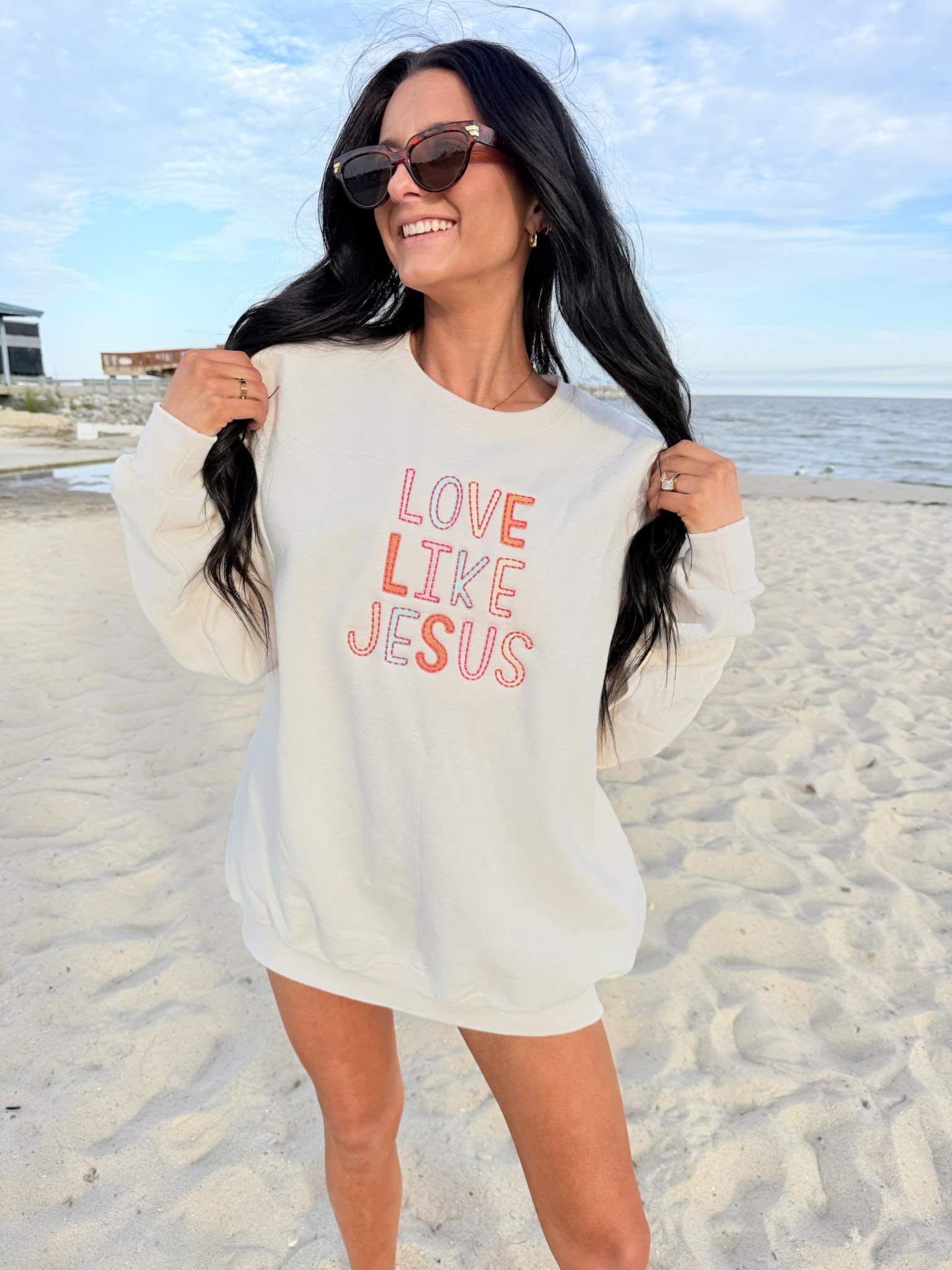 Woman wearing a 'Love Like Jesus' embroidery shirt on a beach