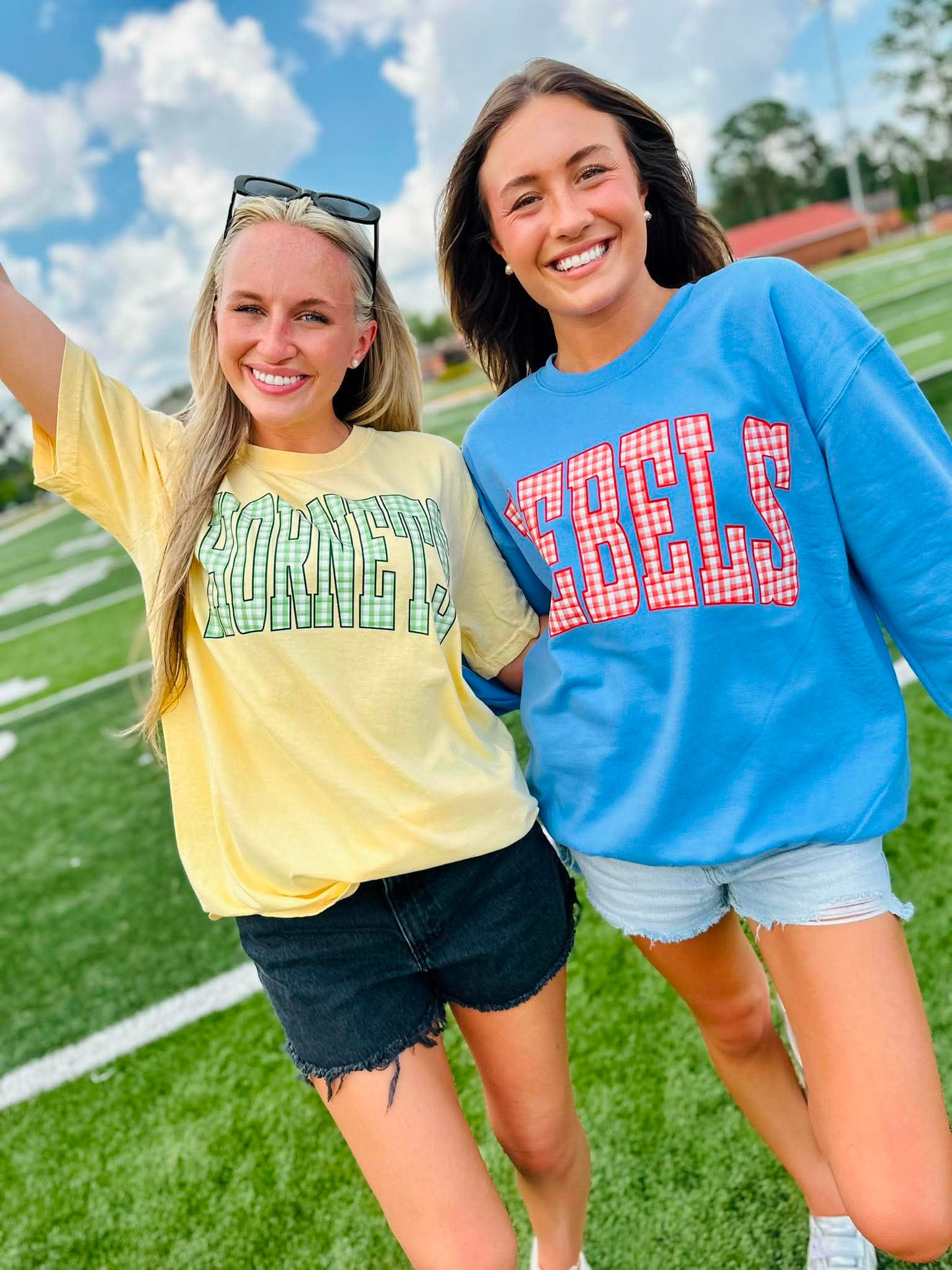 Two women standing on a football field wearing 'KENTUCKY' and 'REELS' shirts.