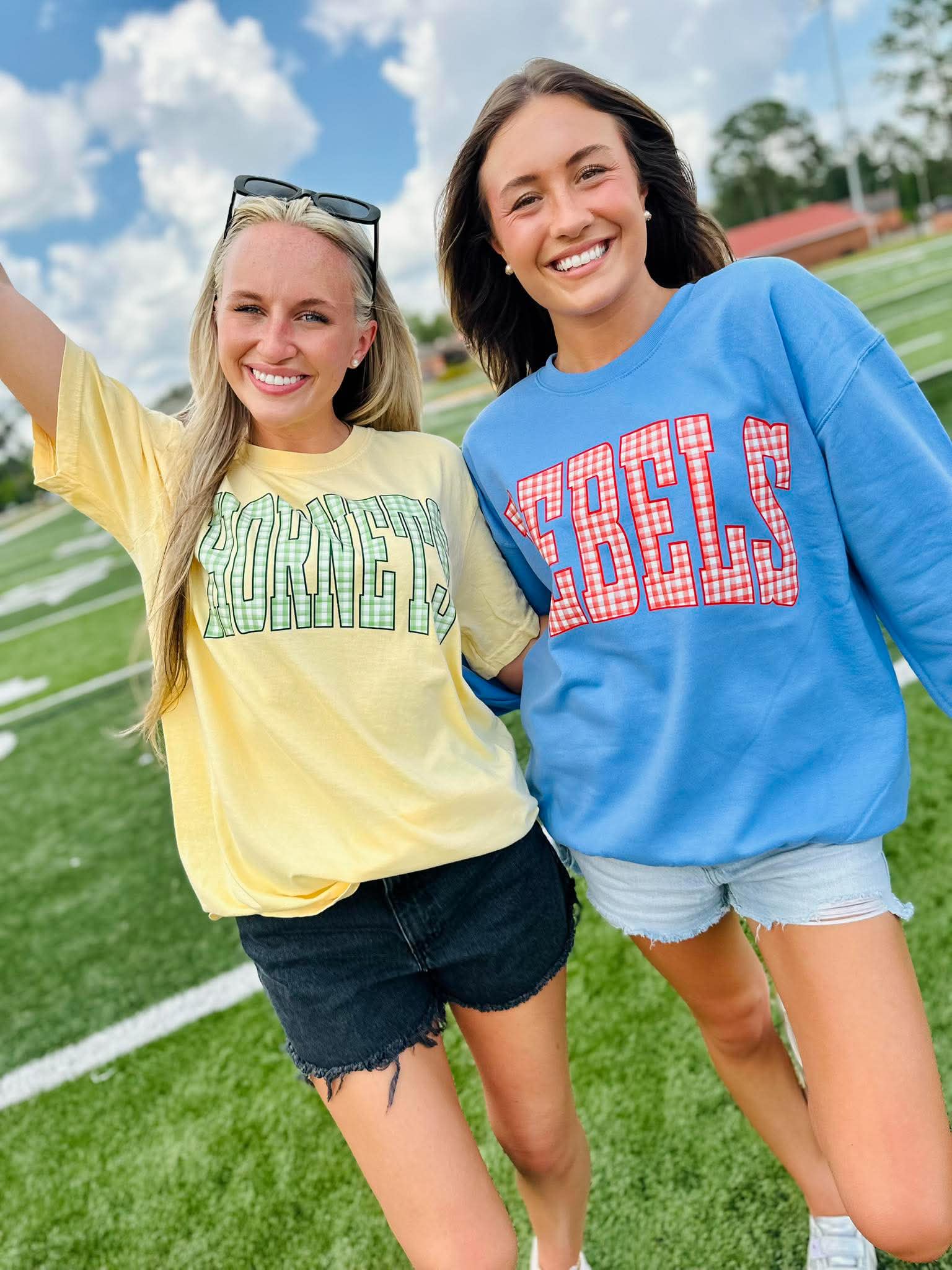 Two women standing on a football field wearing 'KENTUCKY' and 'REELS' shirts.