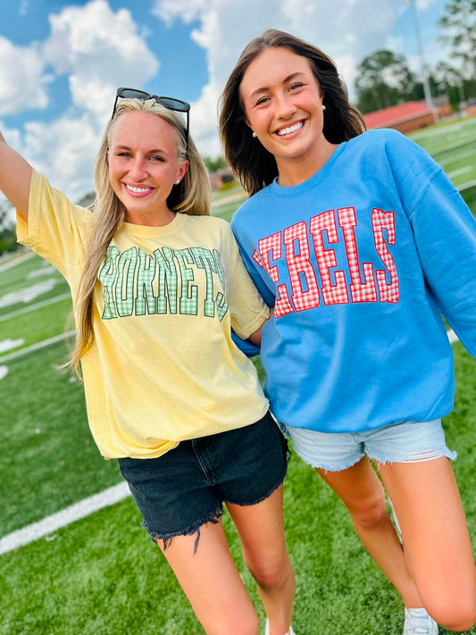 Two women standing on a football field wearing 'KENTUCKY' and 'REELS' shirts.