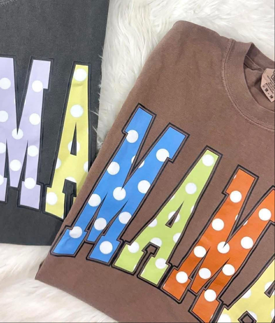 Two sweatshirts with colorful 'MAMA' text on a white surface