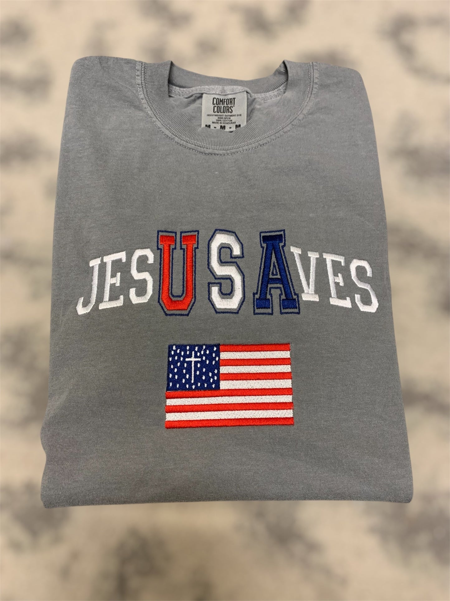 Gray t-shirt with 'JESUS SAVE' text and American flag on a beige background