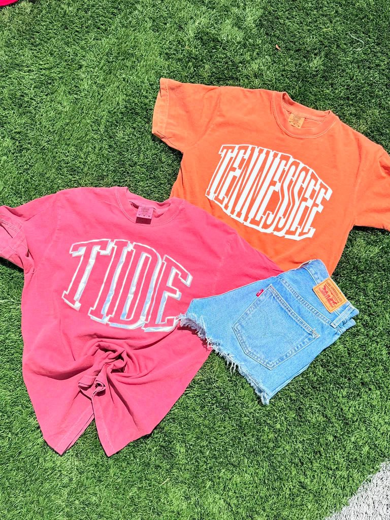 Two t-shirts with 'TIDE' and 'TENNESSEE' text on grass