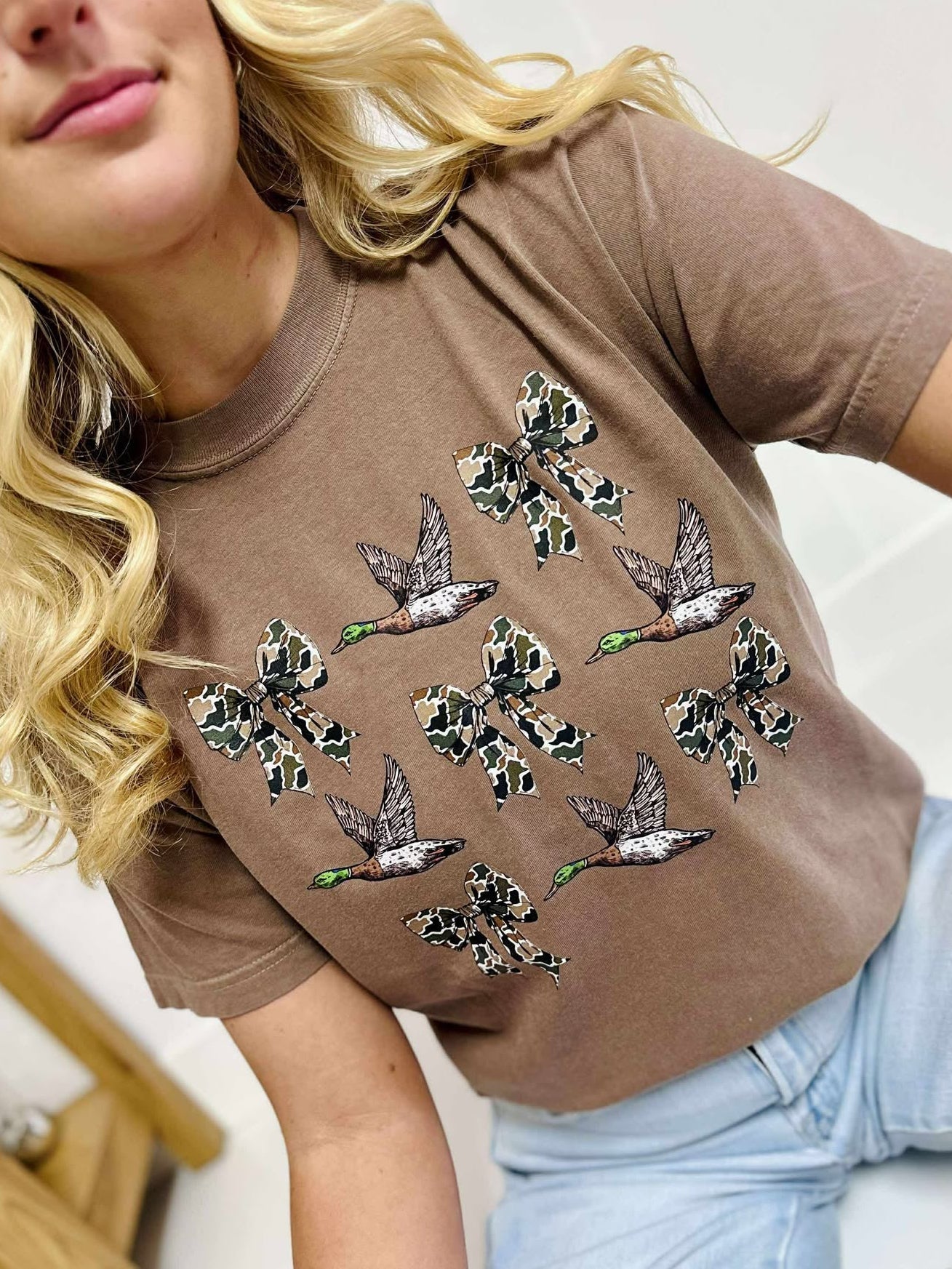 Woman wearing a Espresso t-shirt with duck bow designs on a white background