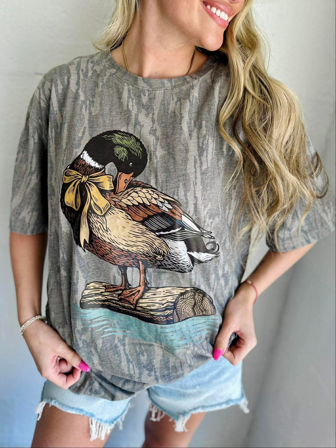 Woman wearing a gray t-shirt with a duck graphic design.